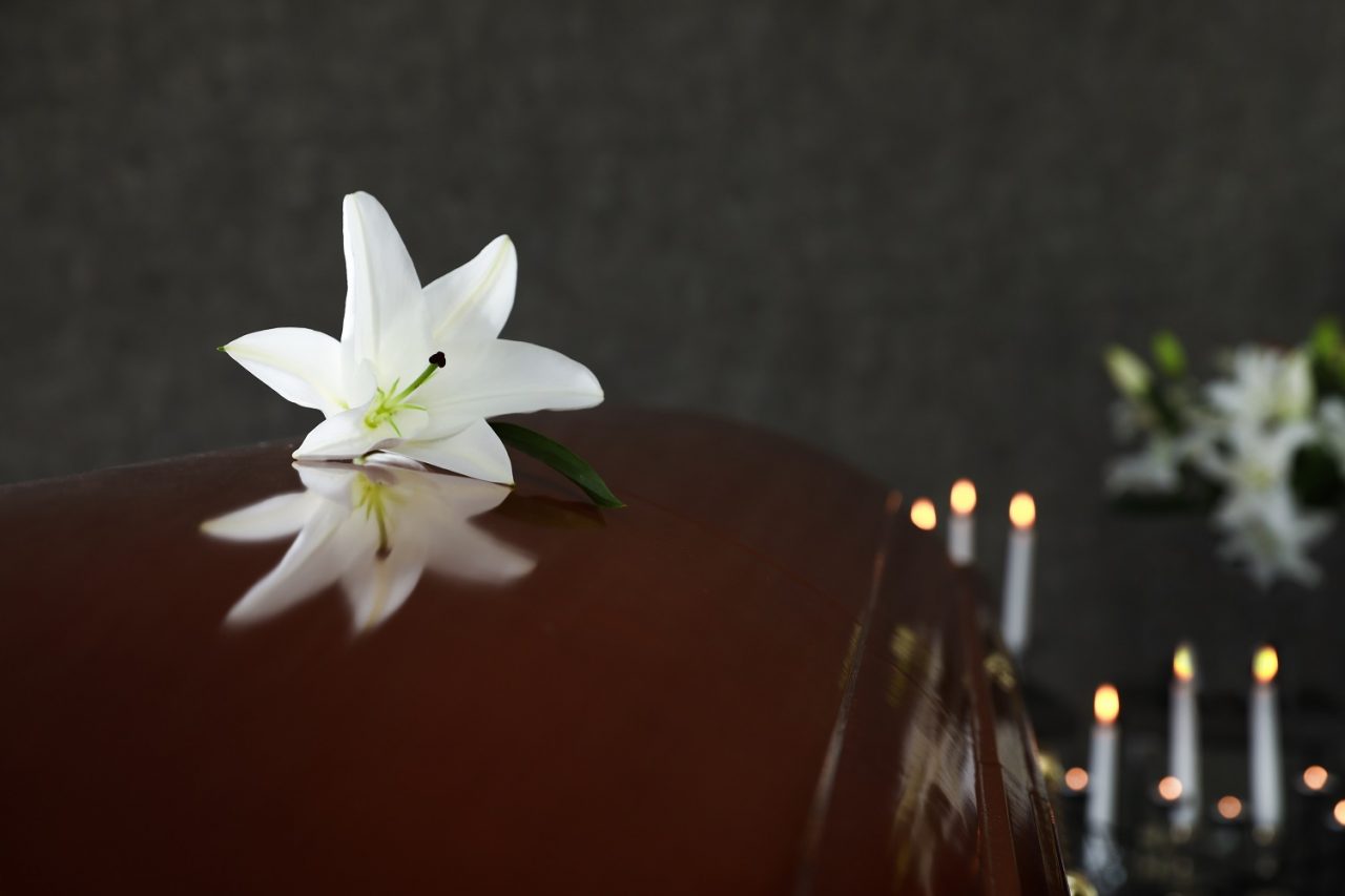 Wooden casket with white flowers and candles at a funeral home