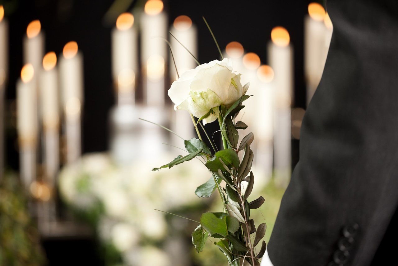 man with white roses at funeral service